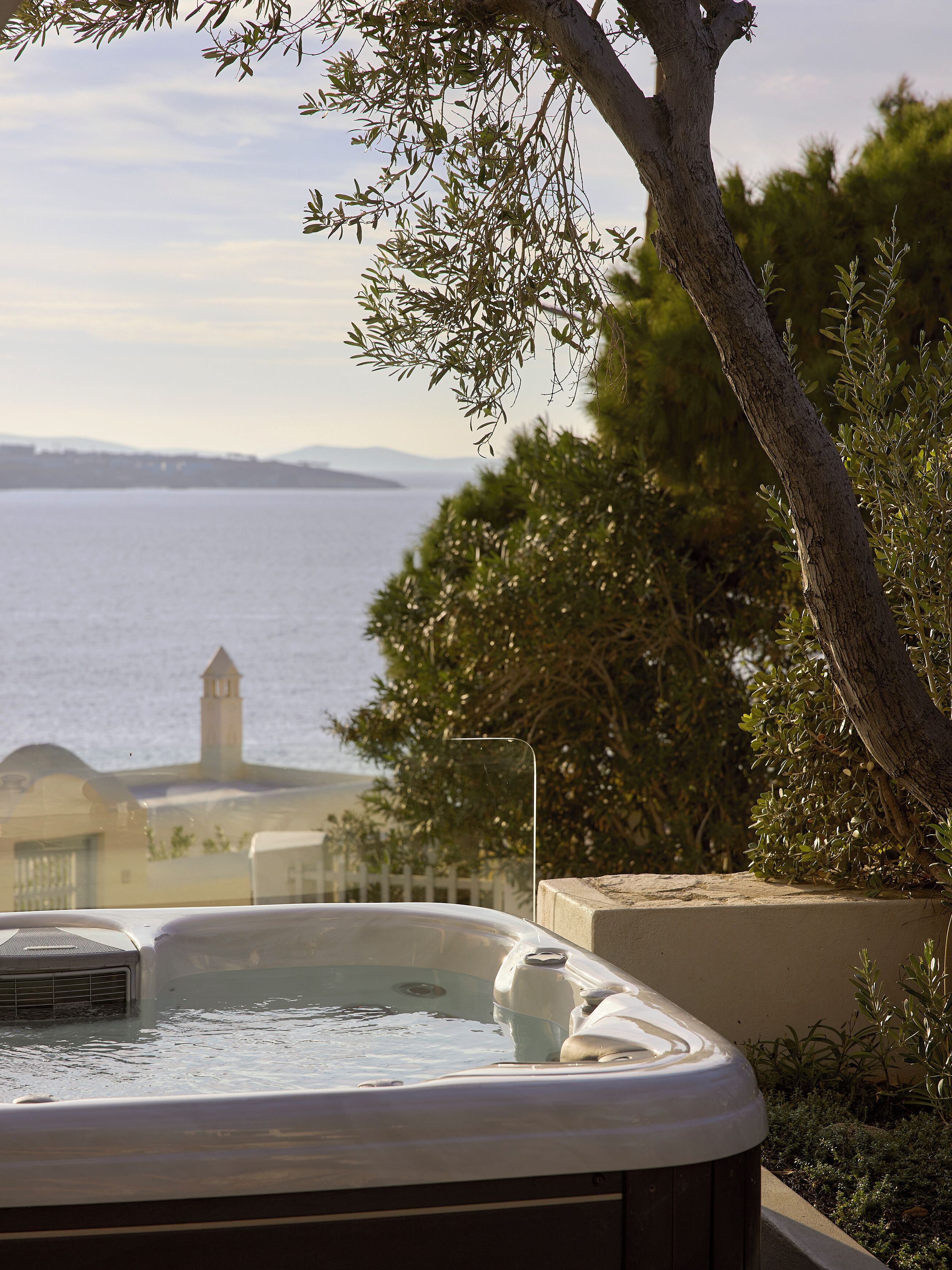 A hot tub with a view of the sea and a building in the background.