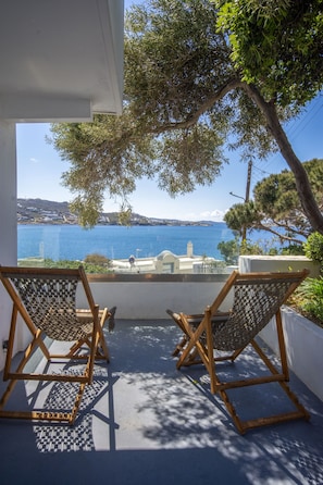 A balcony with two wooden chairs and a view of the sea.