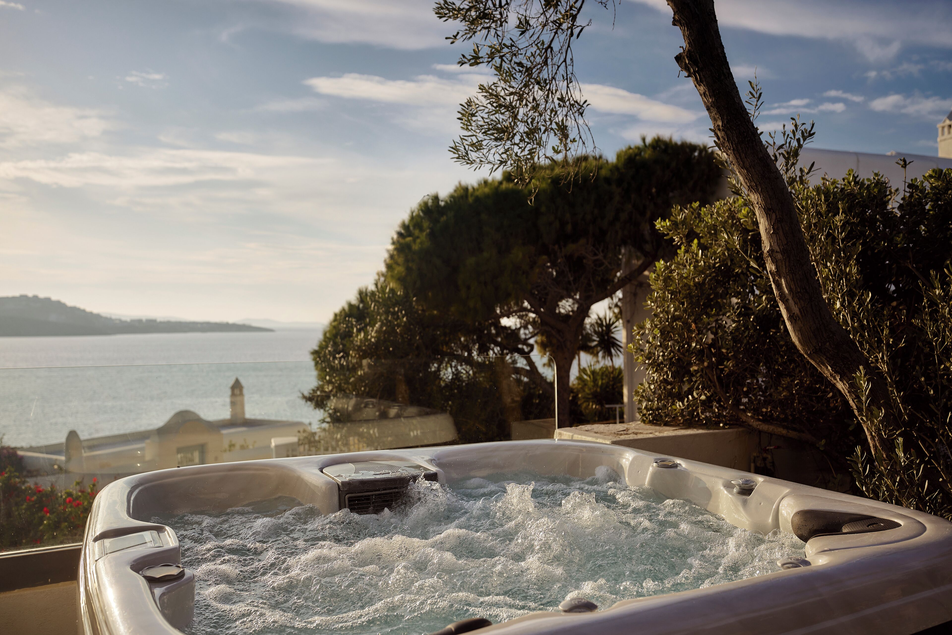 A hot tub with a view of the sea and a lighthouse in the background.