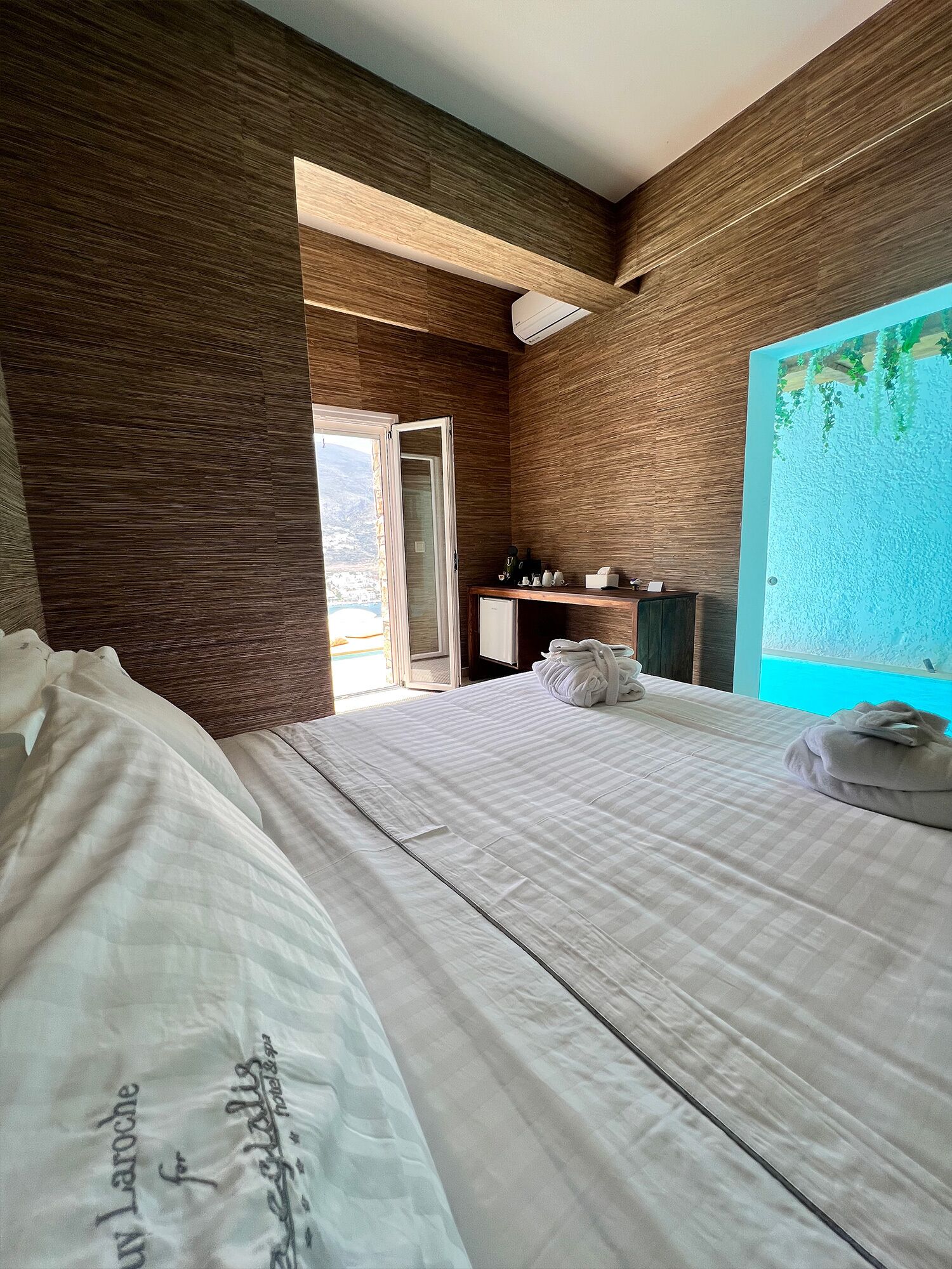 A hotel room with two beds, a desk, and a view of a mountainous landscape.