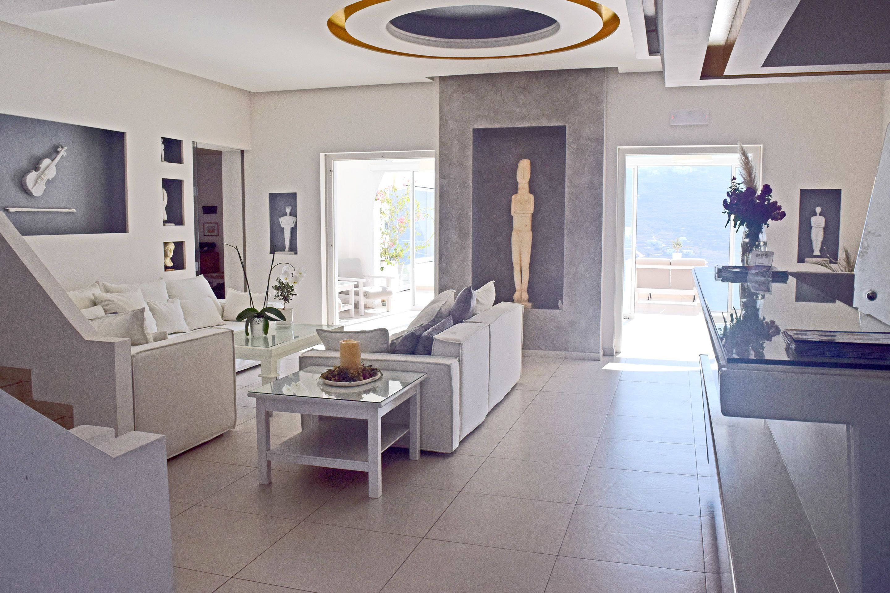 Una sala de estar moderna con un sofá blanco, una mesa de centro de vidrio y una escultura en la pared.