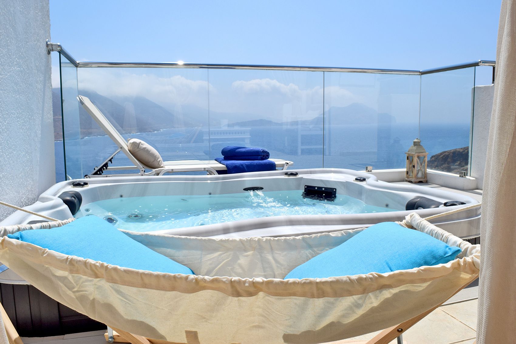 Un jacuzzi con cojines azules, un farol y vistas al mar y a las montañas.