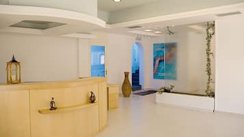 A reception area with a wooden reception desk, a large vase, and a painting on the wall.