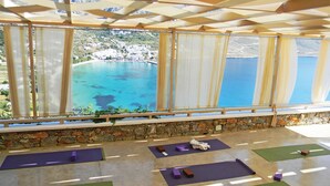Una stanza con vista sulla costa, tappetini e blocchi da yoga sul pavimento.