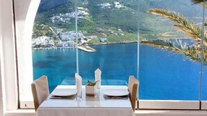 Un tavolo da pranzo con vista diretta sul paesaggio costiero attraverso un'ampia finestra.