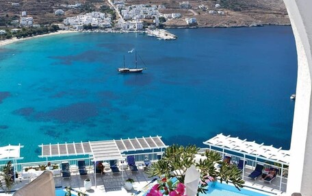 A table set for two with a view of a coastal town and clear blue sea.