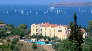 Ein Hotel mit mehreren Balkonen und Blick auf ein Meer mit Segelbooten.