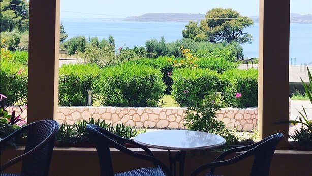 Ein überdachter Sitzbereich mit Blick auf das Meer und viel Grün.