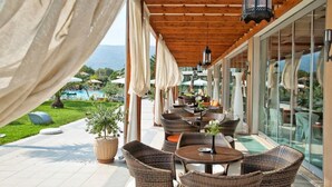 Un patio exterior con mobiliario de mimbre, puertas de cristal y vistas al paisaje.