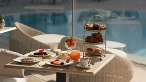 A breakfast tray with pastries, fruits, and juice by a poolside with lounge chairs. - La Residenza Capri (Capri)