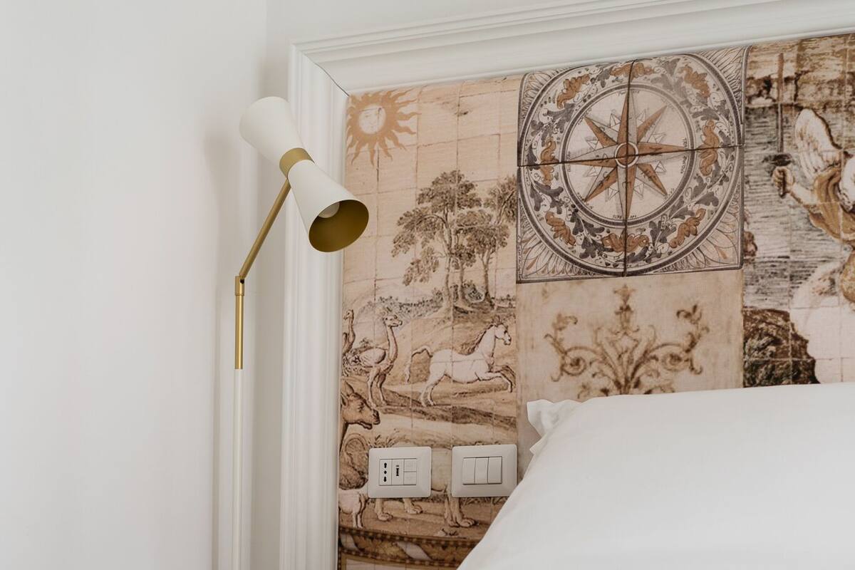 A bedroom with a bed, a wall-mounted lamp, and a decorative tile wall.