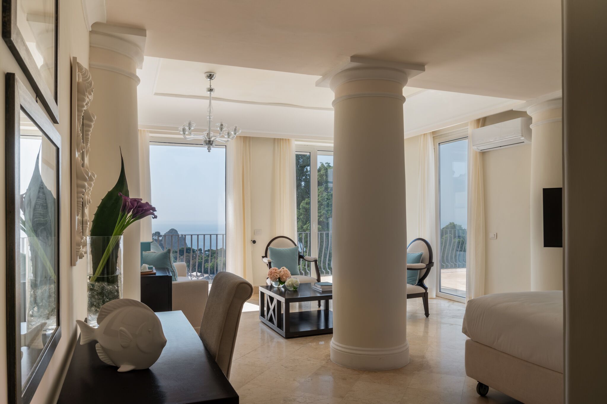 Un salon spacieux avec une grande fenêtre, un lustre et une vue sur la mer.