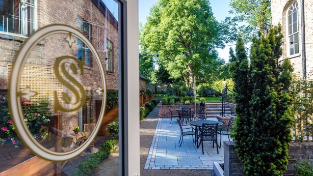 Un edificio de ladrillo con un patio que incluye mobiliario exterior y un jardín.