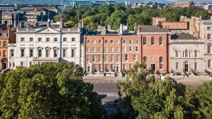 Un paisaje urbano con edificios históricos, cielo despejado y grúas de construcción a lo lejos.