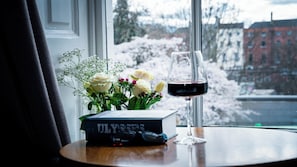A book titled "ULYSSES" on a table with a glass of red wine and a bouquet of flowers.