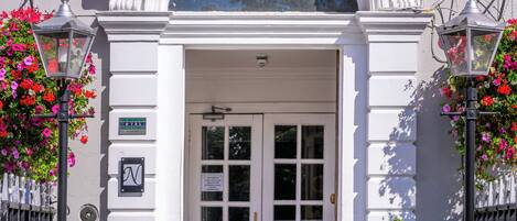 The entrance to Hotel St George with a white facade, a large arched window, and a sign above the door.