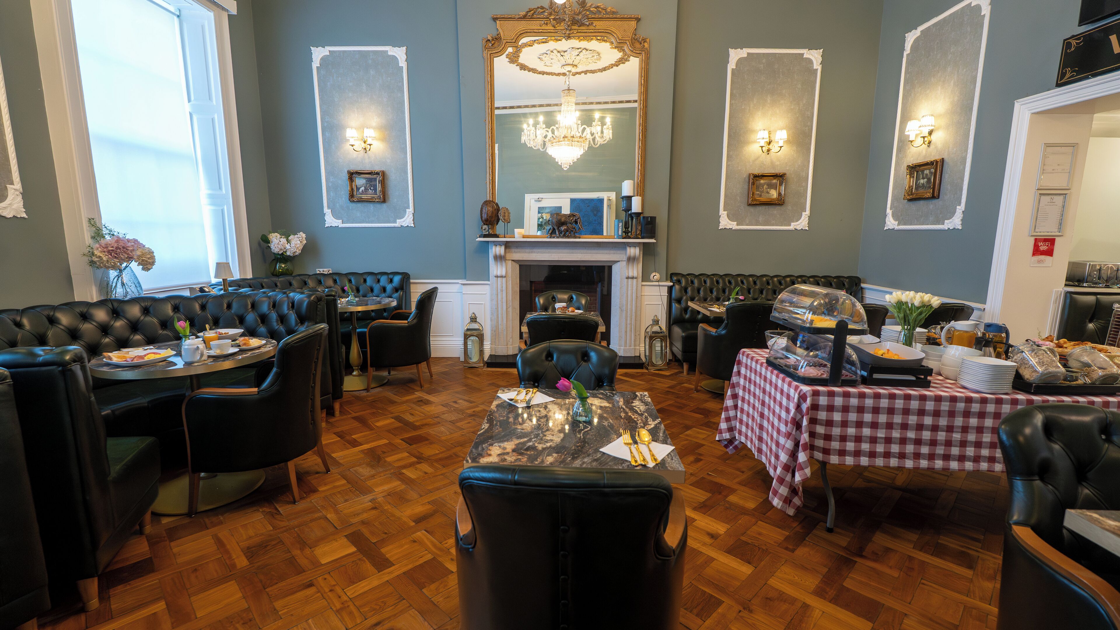 Un espace repas avec des banquettes en cuir noir, une table en marbre et une nappe à carreaux.