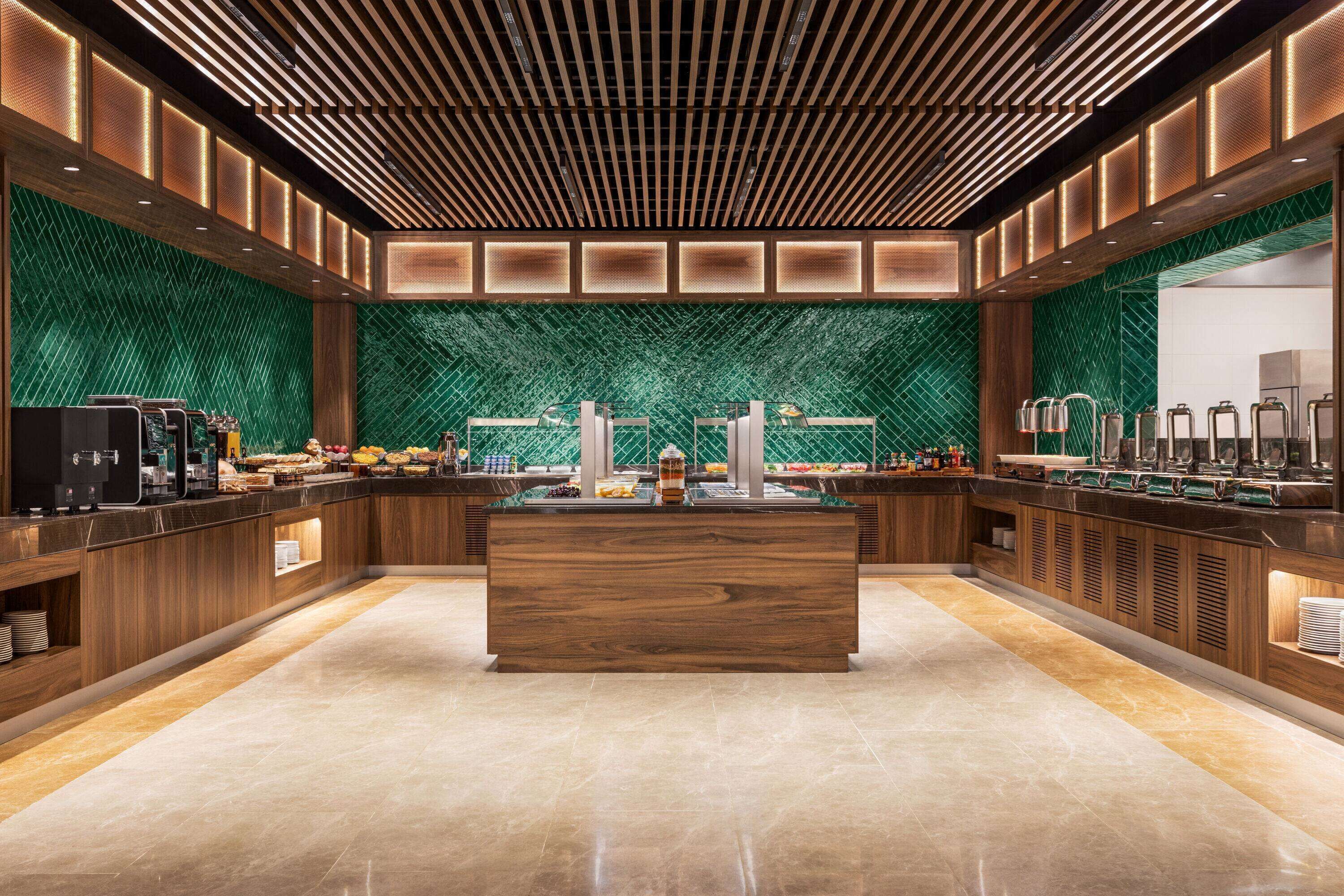 A modern breakfast bar with a central island, green patterned wall, and wooden paneling.
