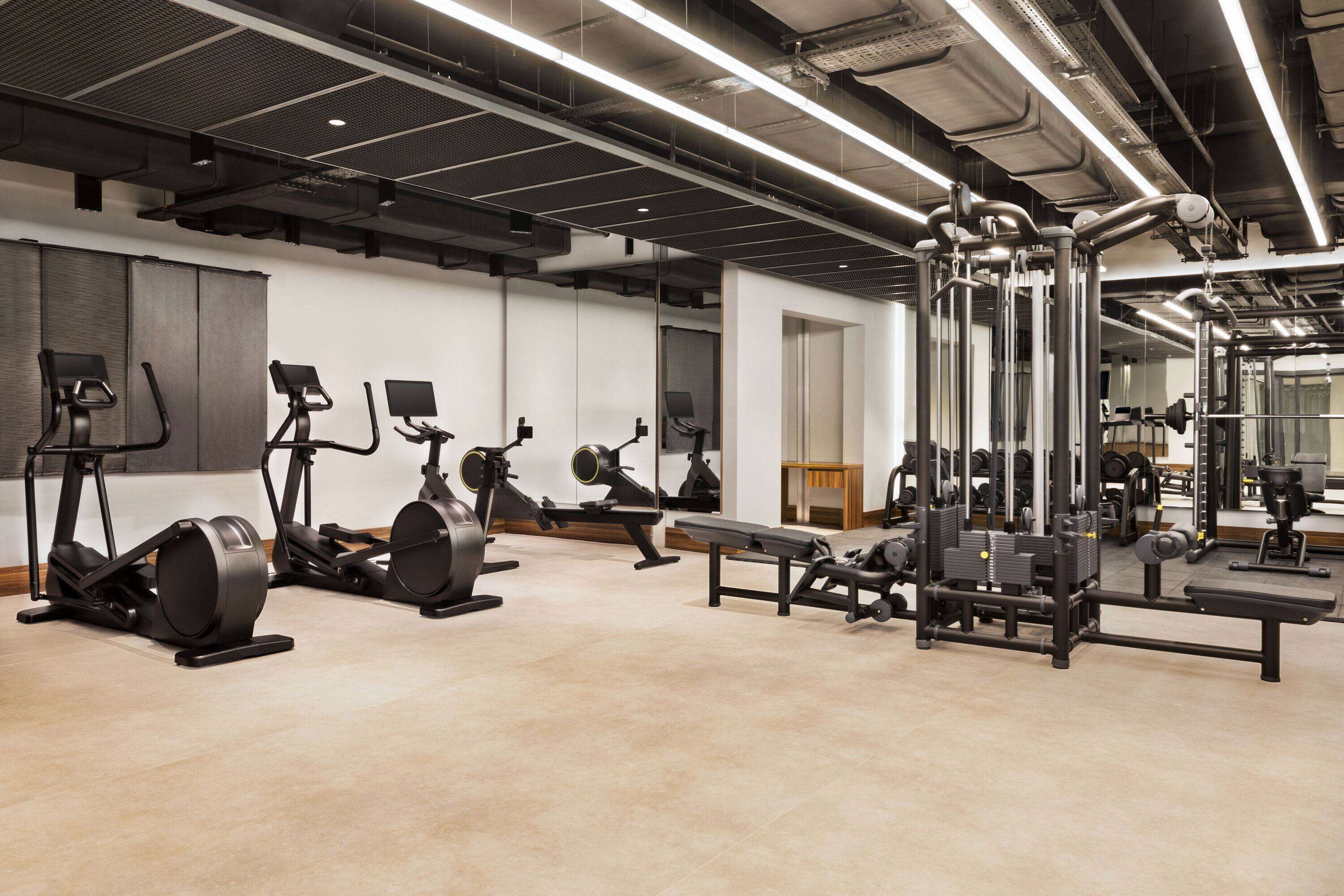 A modern gym with various exercise equipment, including treadmills, stationary bikes, and weight machines.