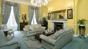A traditional living room with a fireplace, two sofas, a coffee table, and a chandelier.