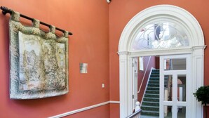 A hallway with a staircase, a chandelier, and a framed picture on the wall.