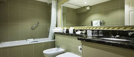 A bathroom with a bathtub, a bidet, a toilet, a sink, and a large mirror.