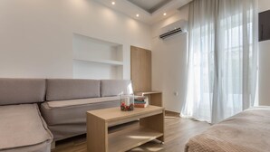 A modern, well-lit room with a sofa, a wooden table with a vase, and a bed. - Mare Naxia (Naxos)