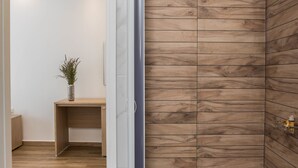 A modern room with wooden panel walls, a wooden floor, a desk with a plant, and a door leading to another room. - Mare Naxia (Naxos)