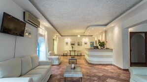 A modern living room with a sofa, a coffee table, and a reception desk. - Mare Naxia (Naxos)