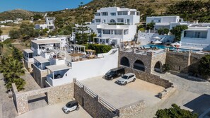 A coastal property with white buildings, a swimming pool, and a stone wall.