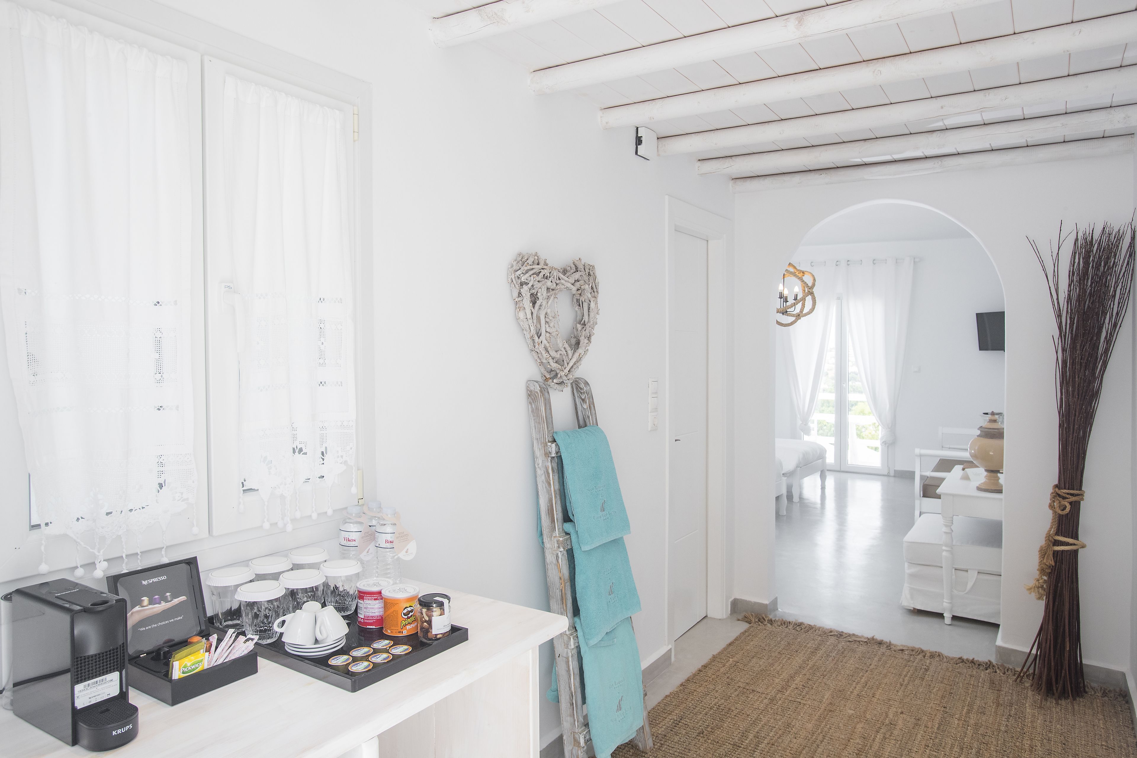 A clean, white room with a coffee station, a ladder with a towel, and a rustic decor.