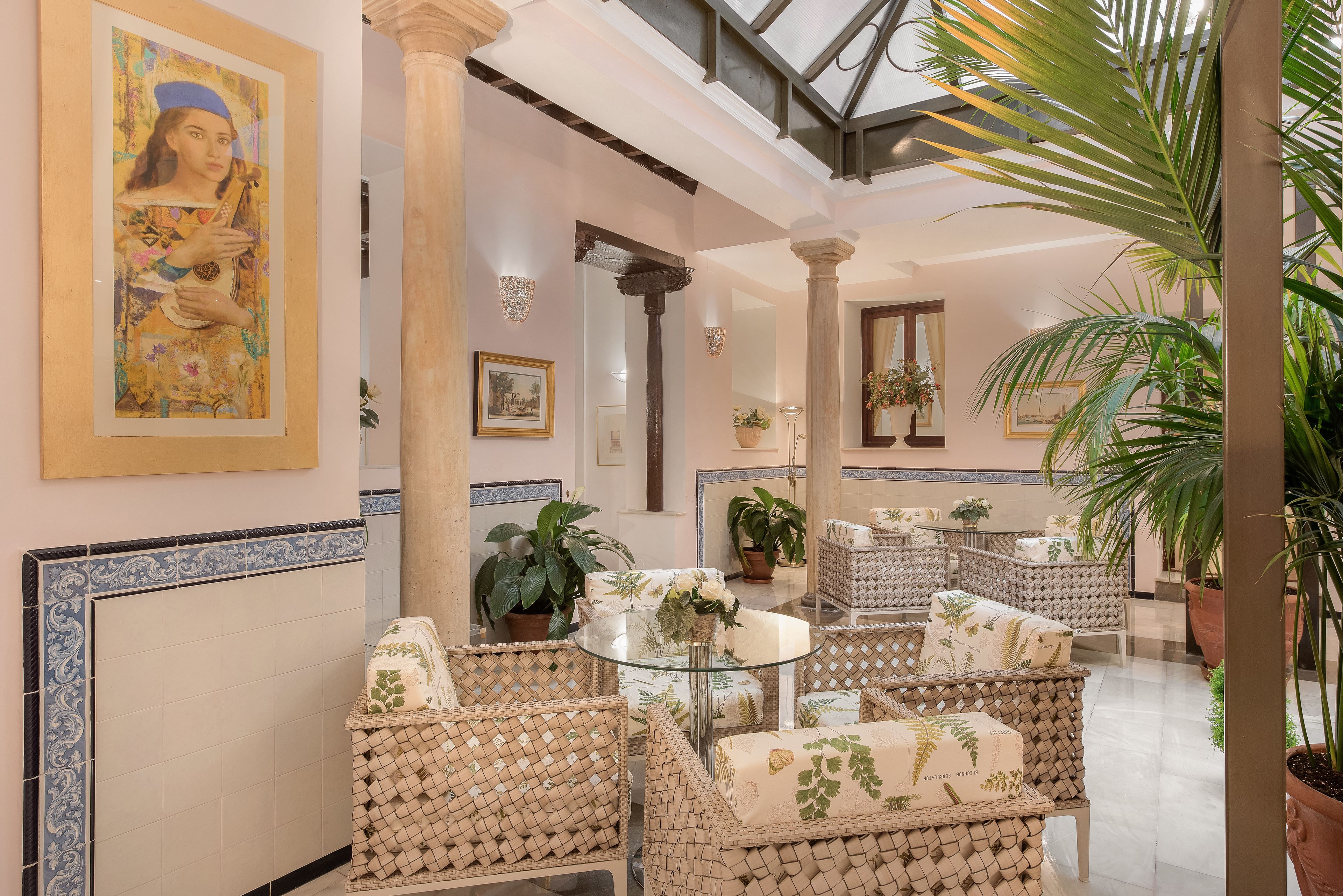 Un amplio espacio interior con muebles de mimbre, una mesa de cristal y plantas en macetas.