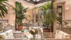 Un amplio espacio interior con muebles de mimbre, plantas en macetas y una mesa de vidrio.