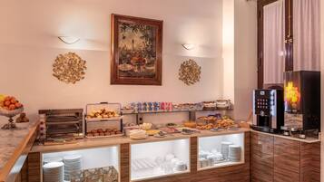 Un bufé de desayuno con diferentes opciones de comida, una máquina de café y un cuadro decorativo en la pared.