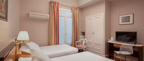 A hotel room with two beds, a desk with a chair, a television, and a window with curtains.