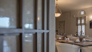 Una cocina moderna con una isla central, sillas blancas y una lámpara colgante.