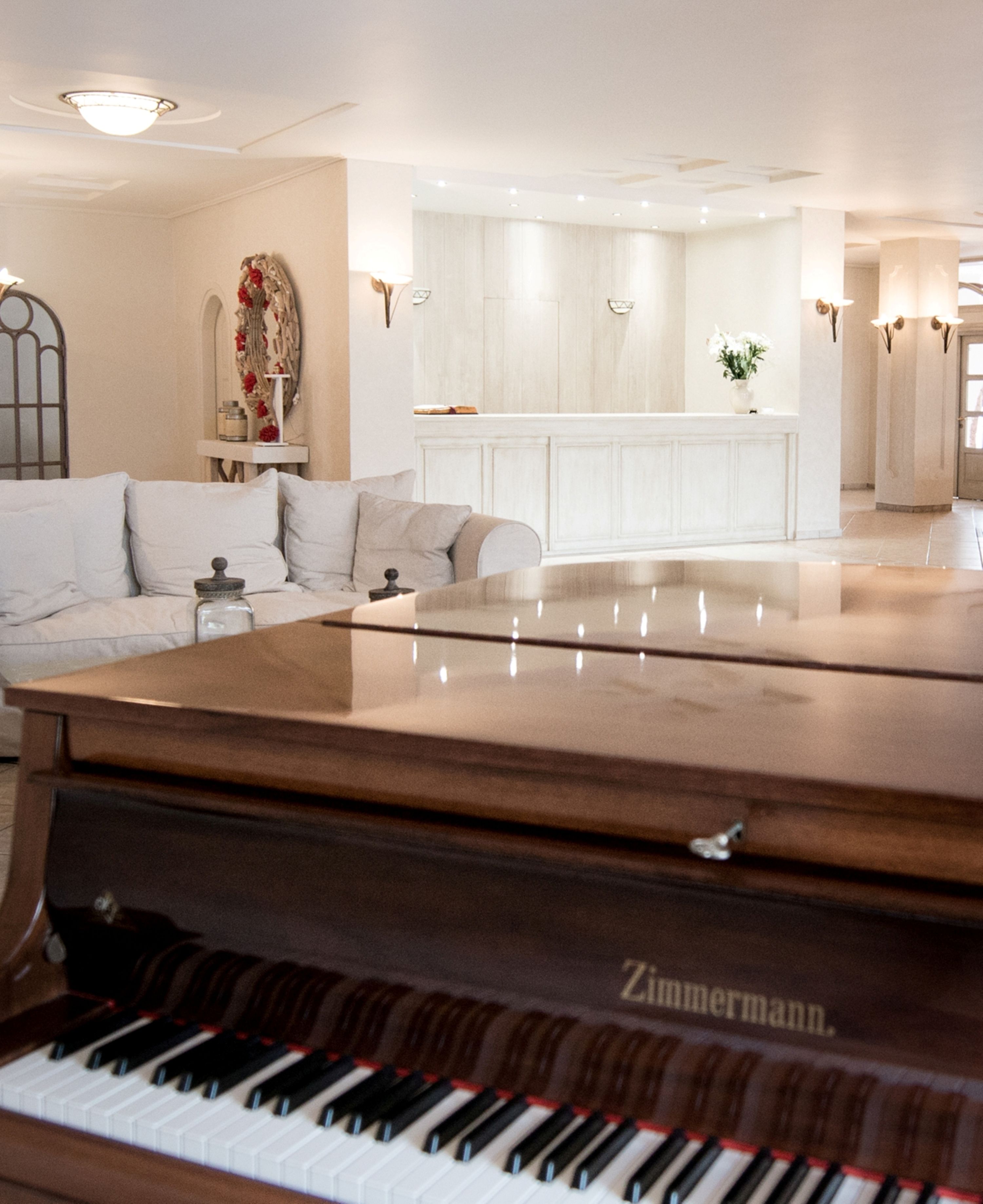 A living room with a grand piano, a sofa, and a decorative mirror.