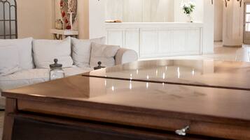 A living room with a grand piano, a sofa, and a decorative mirror.