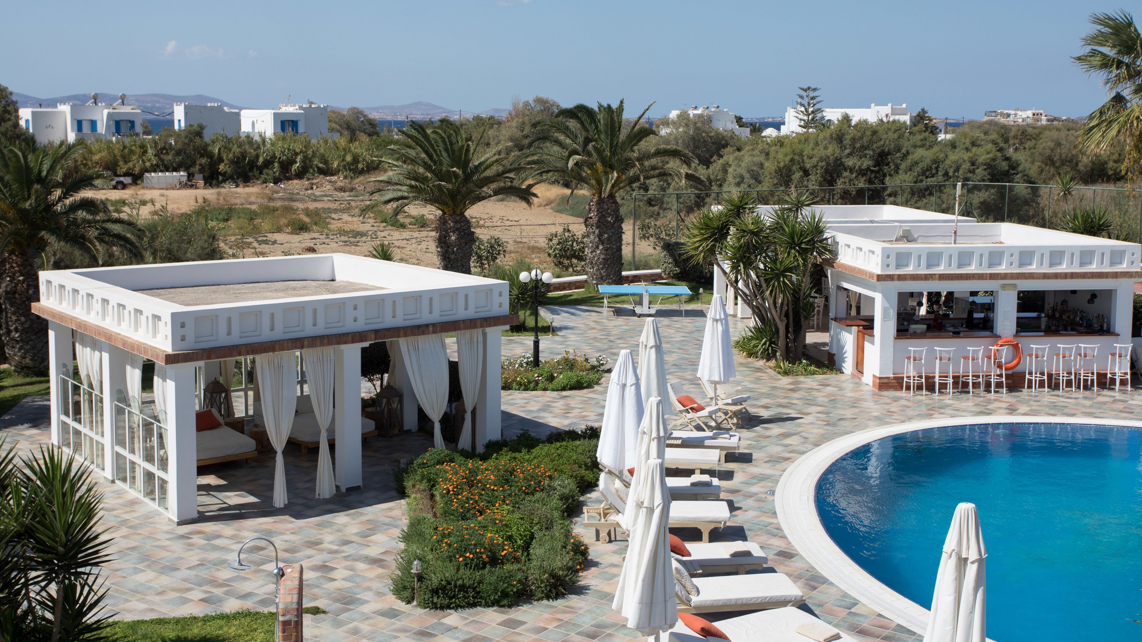 A pool area with lounge chairs and umbrellas, a bar area with seating, and a view of the surrounding landscape.