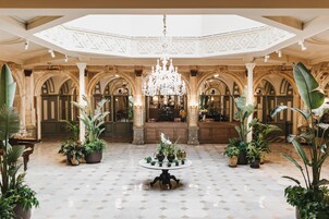 A spacious lobby with a high ceiling, ornate columns, and a central chandelier.