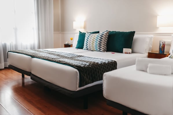Una habitación de hotel con una cama grande, dos mesitas de noche y una pequeña mesa con una lámpara.