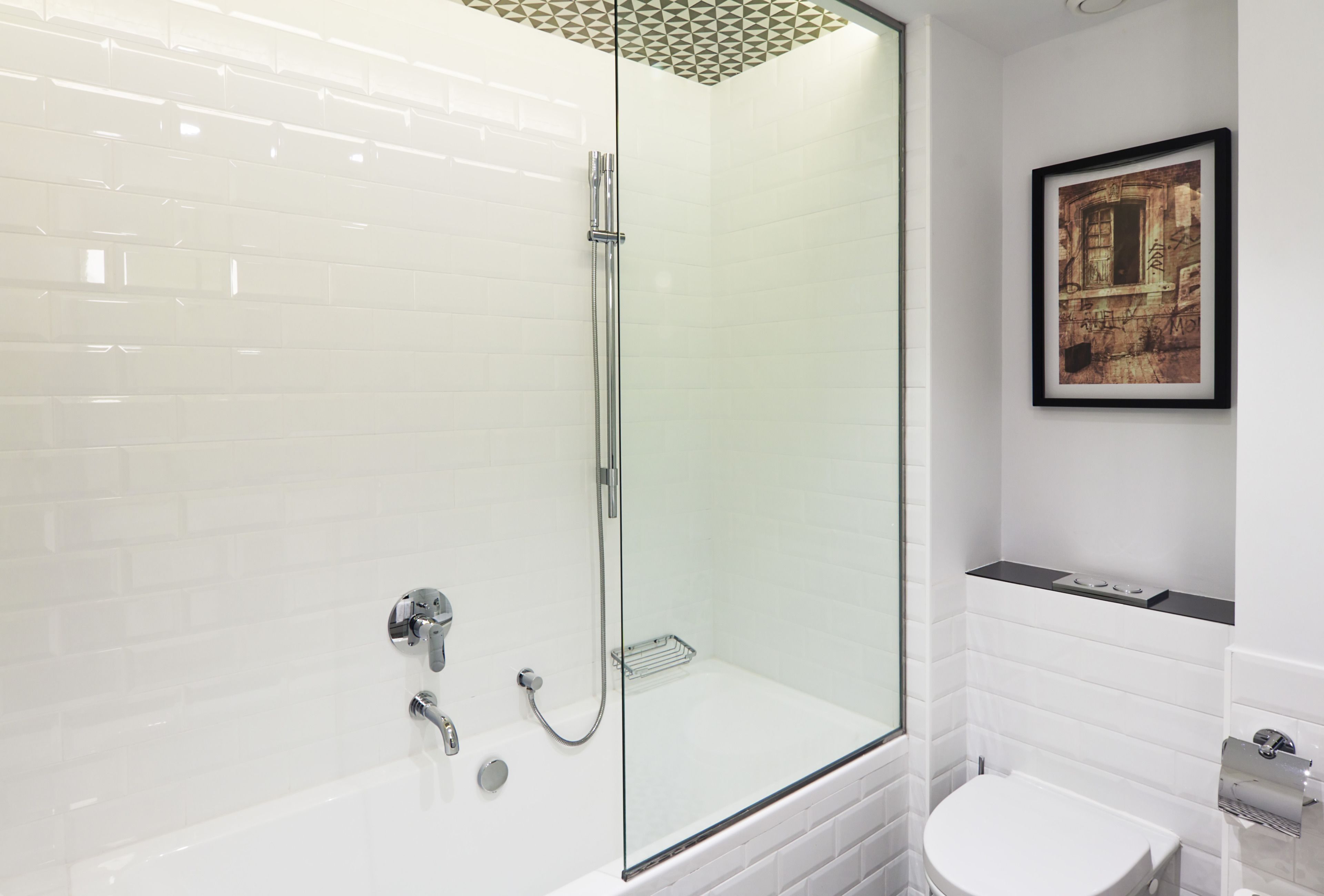 Een moderne badkamer met een douchecabine van glas, een witte badkuip en een toilet.