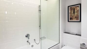 Un baño moderno con ducha de vidrio, bañera blanca y retrete.