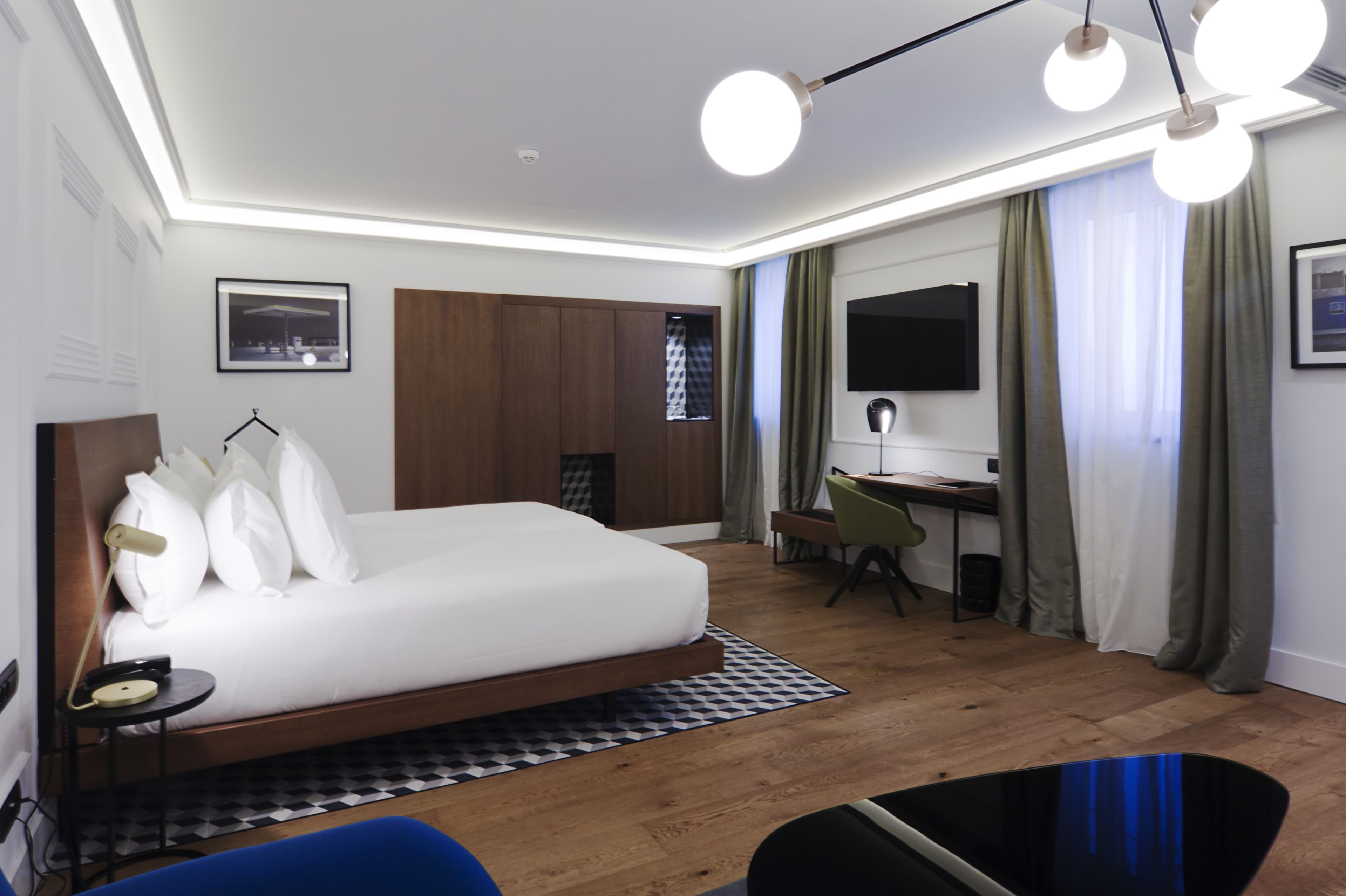 A modern hotel room with a bed, desk, and seating area.