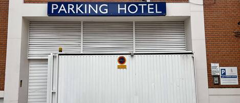 A closed garage door with a sign reading "PARKING HOTEL" above it.