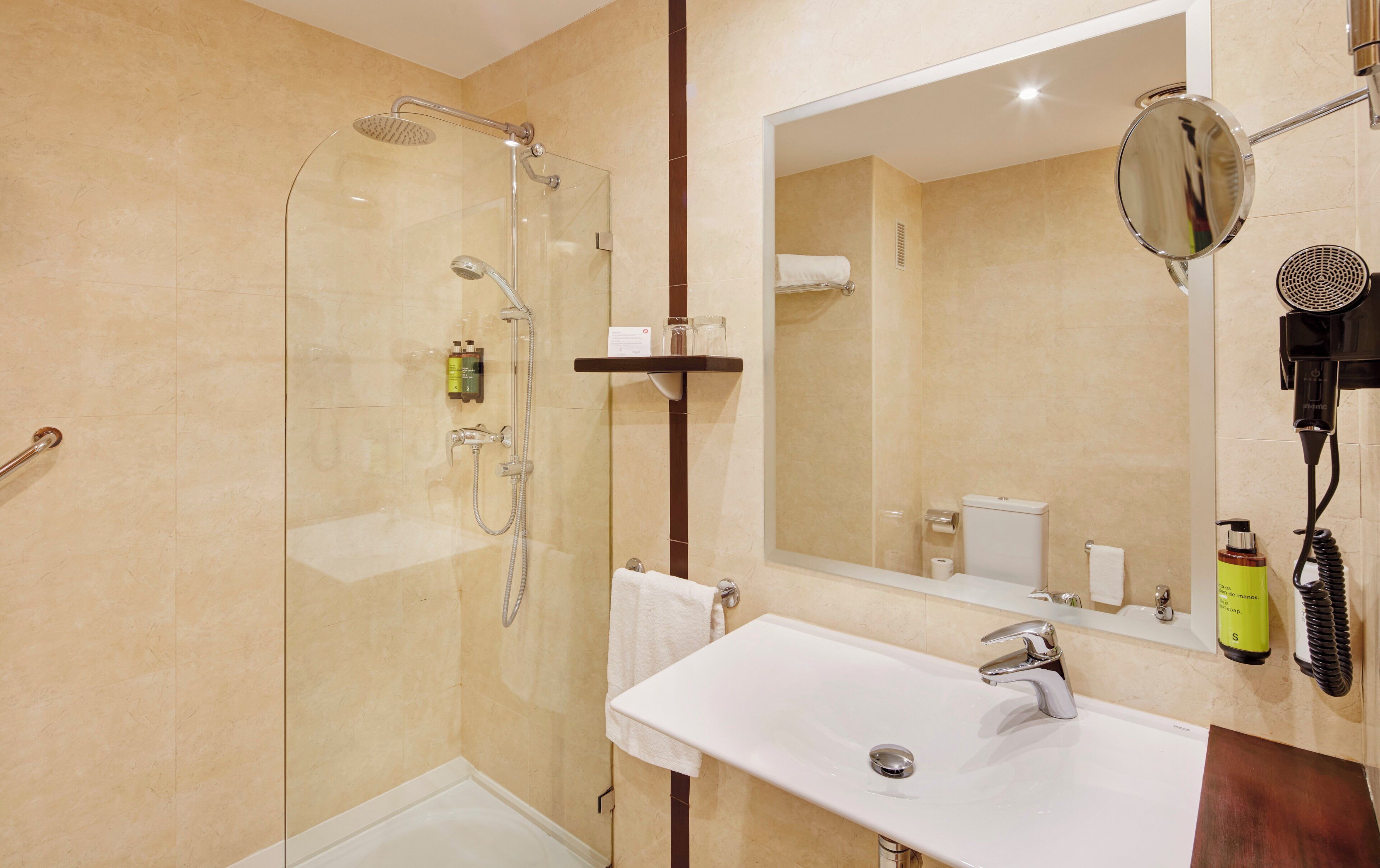 Un baño moderno con ducha envuelta en vidrio, un lavabo blanco y un espejo grande.