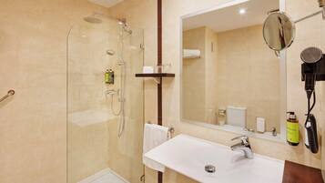 Un baño moderno con ducha envuelta en vidrio, un lavabo blanco y un espejo grande.
