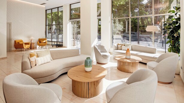 Una sala de estar moderna con un sofá modular, mesas de centro redondas y un ventanal con vistas al exterior.