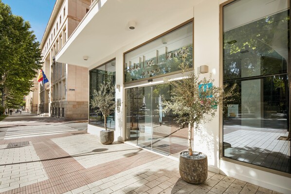 A hotel entrance with large glass doors, potted plants, and a clear view of the street. - Hotel Sercotel Los Llanos (Albacete)