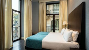 Una habitación de hotel con una cama grande, un balcón con vistas y una ventana con cortinas.